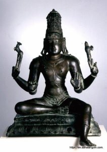 A seated Shiva holds an axe and deer in his hands.